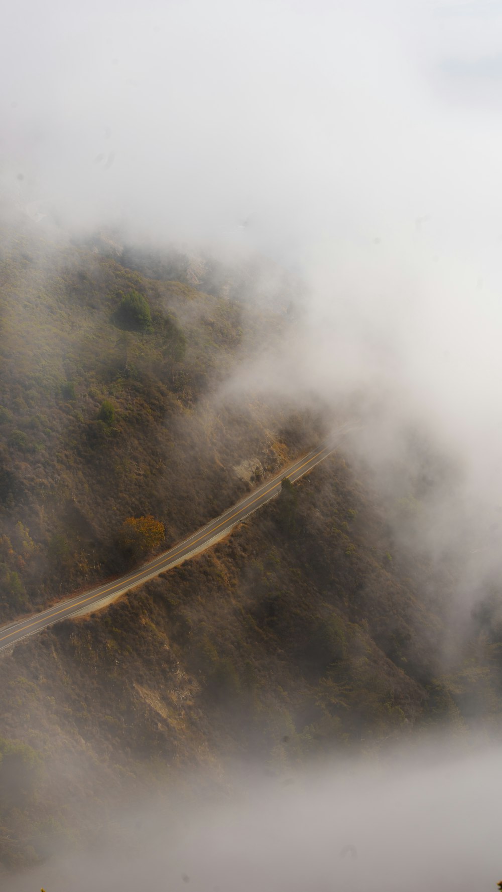 a foggy mountain with a winding road in the foreground