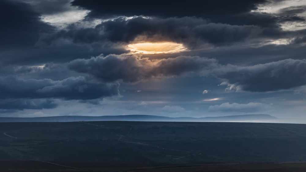 the sun is shining through the clouds over the hills