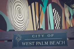 a city of west palm beach sign in front of a mural
