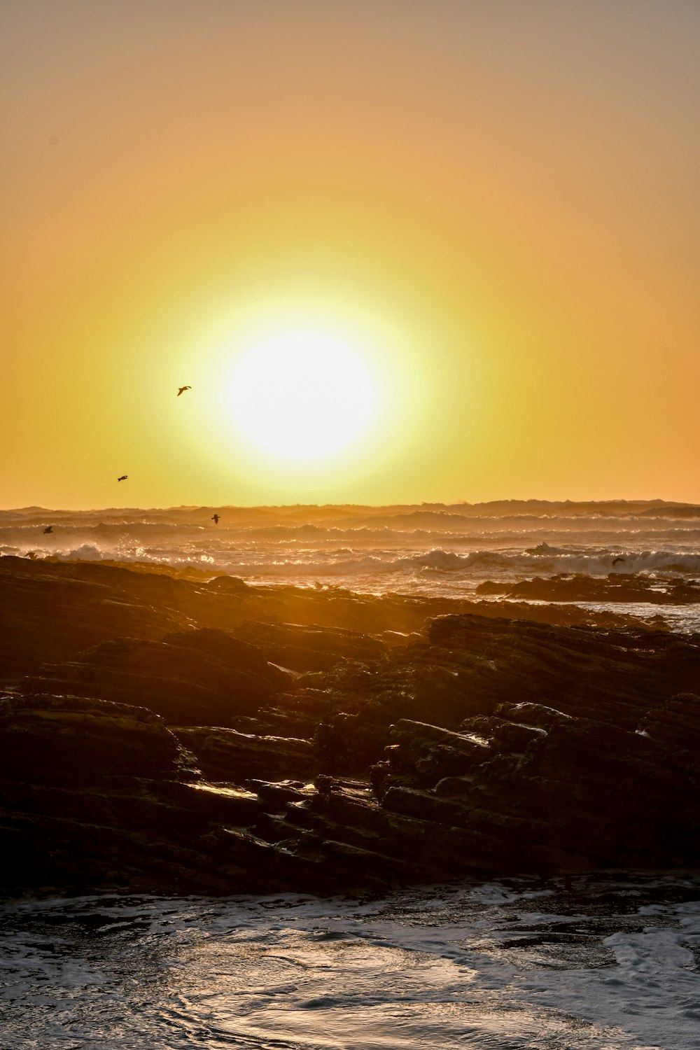 the sun is setting over the ocean with waves