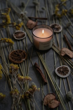 A rustic candle surrounded by dried flowers and natural elements.