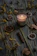 A softly lit candle nestled among dried florals on a rustic wooden shelf.