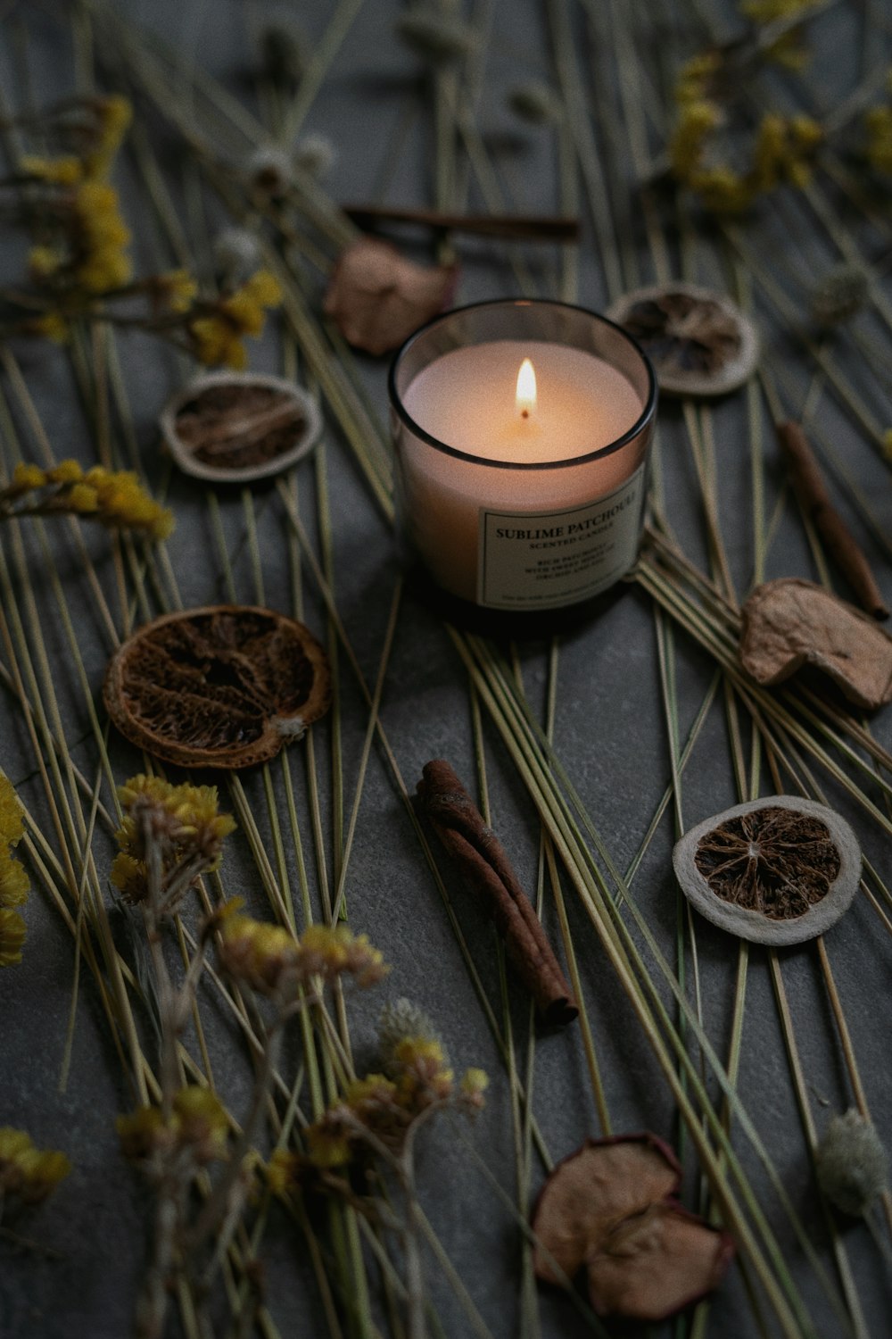 a candle sitting on top of a table surrounded by dried flowers