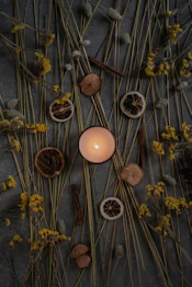a lit candle surrounded by dried flowers and twigs