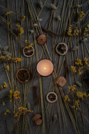 a lit candle surrounded by dried flowers and twigs