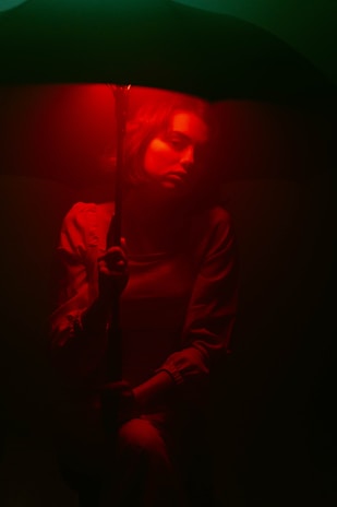 A dramatic view of Umbrella Corp. guards patrolling under harsh red lighting, shadows casting long shapes.