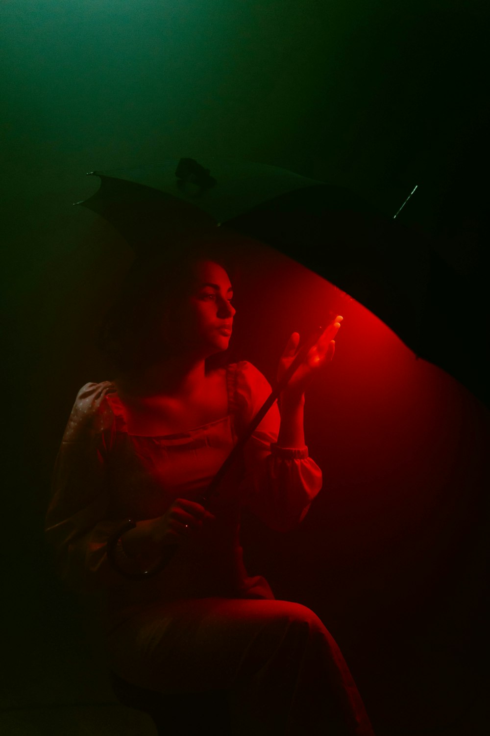 a woman sitting under an umbrella in the dark