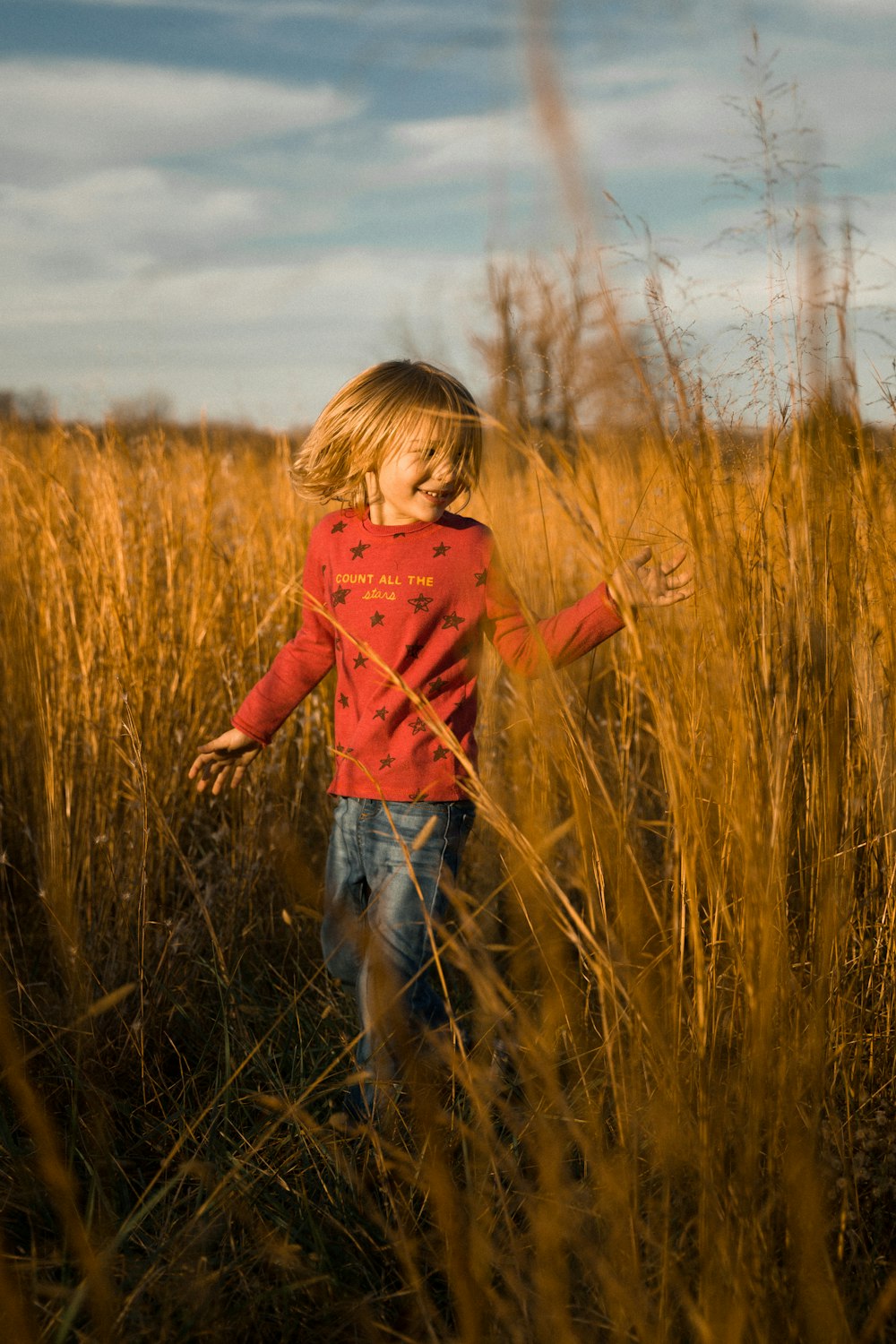 a little girl standing in a field of tall grass