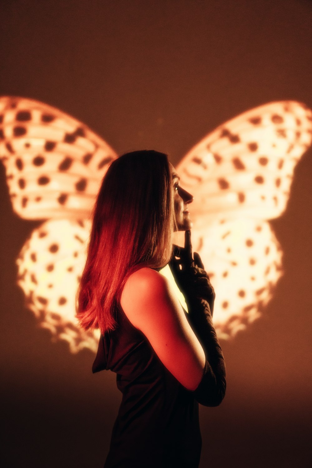 a woman standing in front of a butterfly projected on a wall