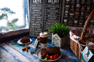a table topped with a plate of cake next to a cup of coffee