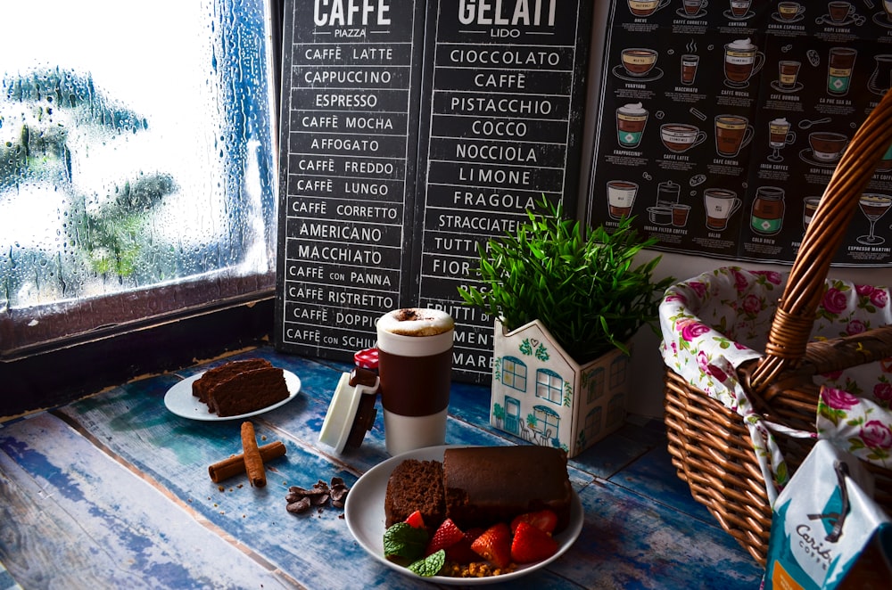 a table topped with a plate of cake next to a cup of coffee