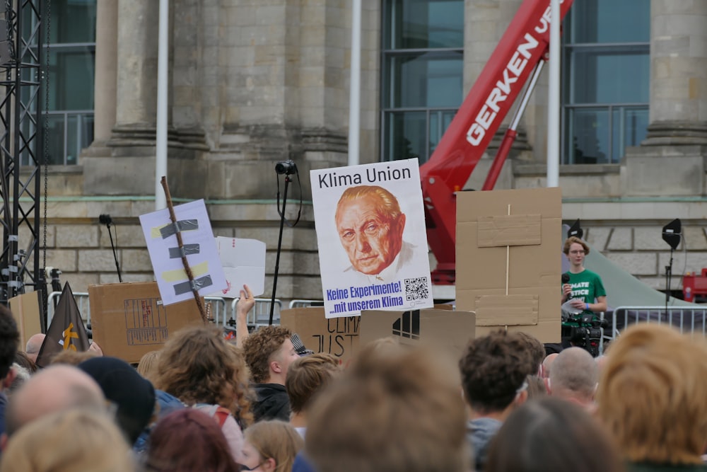 a crowd of people standing around a man holding a sign