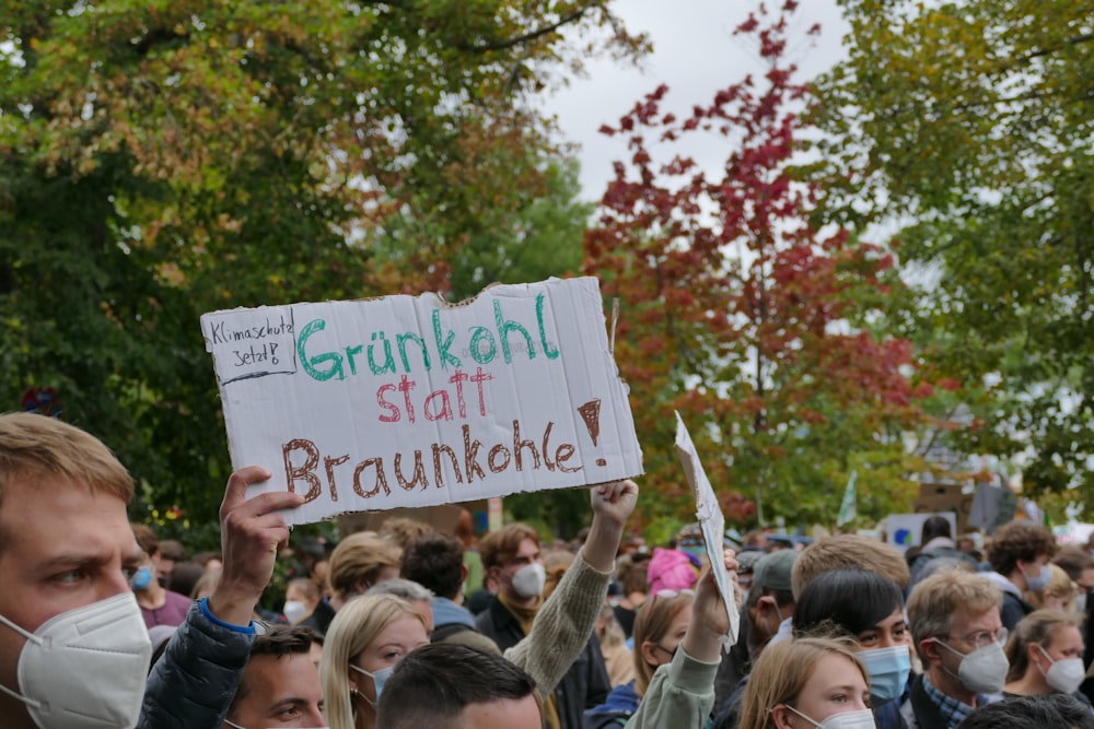 a group of people holding signs and wearing masks