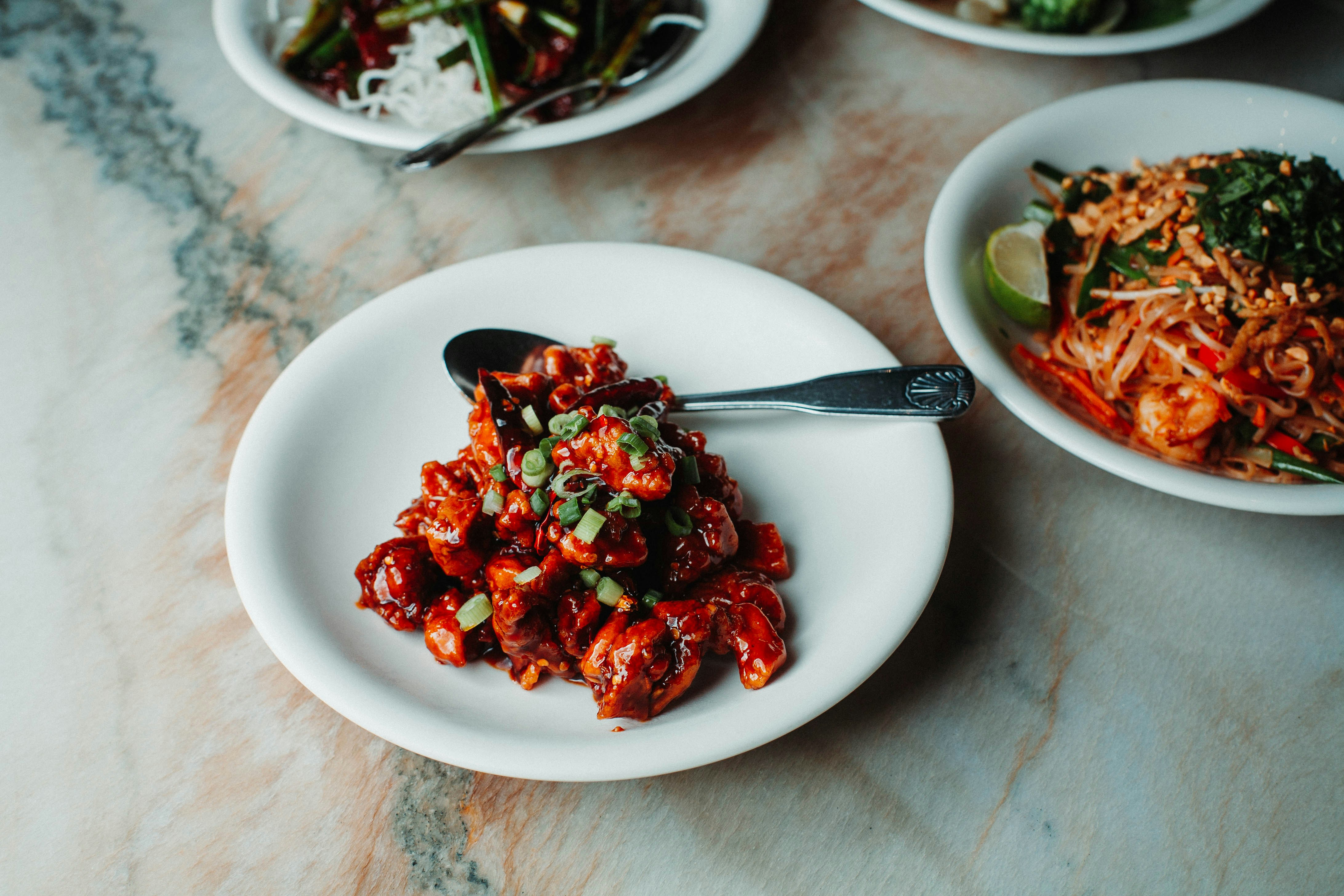 a white plate topped with food next to a bowl of salad, Chinese food in LA. 