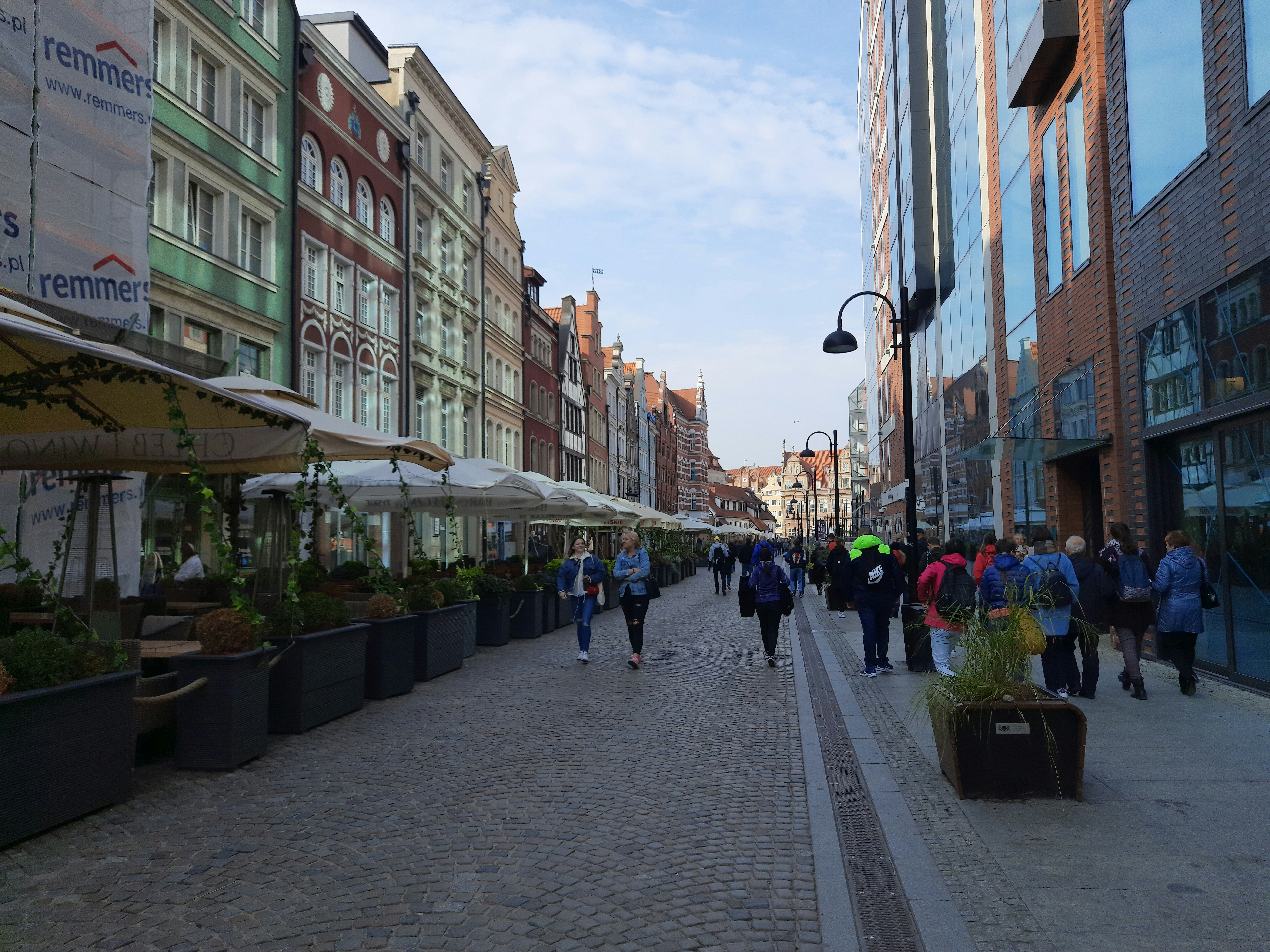 a group of people walking down a street next to tall buildings