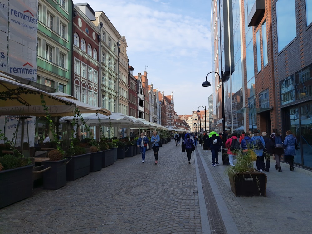 a group of people walking down a street next to tall buildings