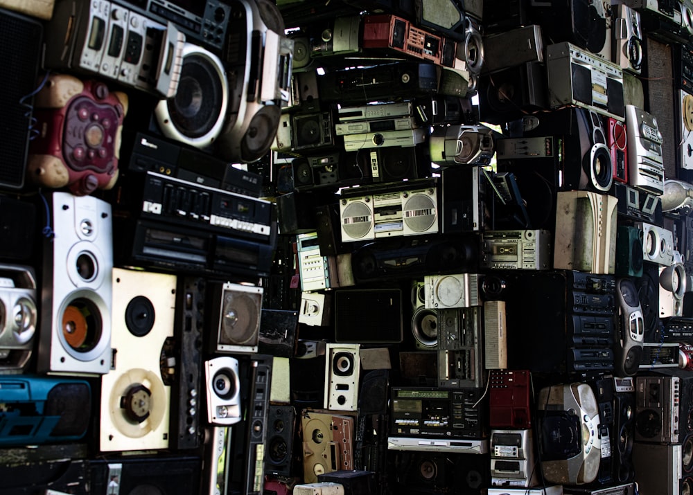 a large amount of old stereos are stacked on top of each other