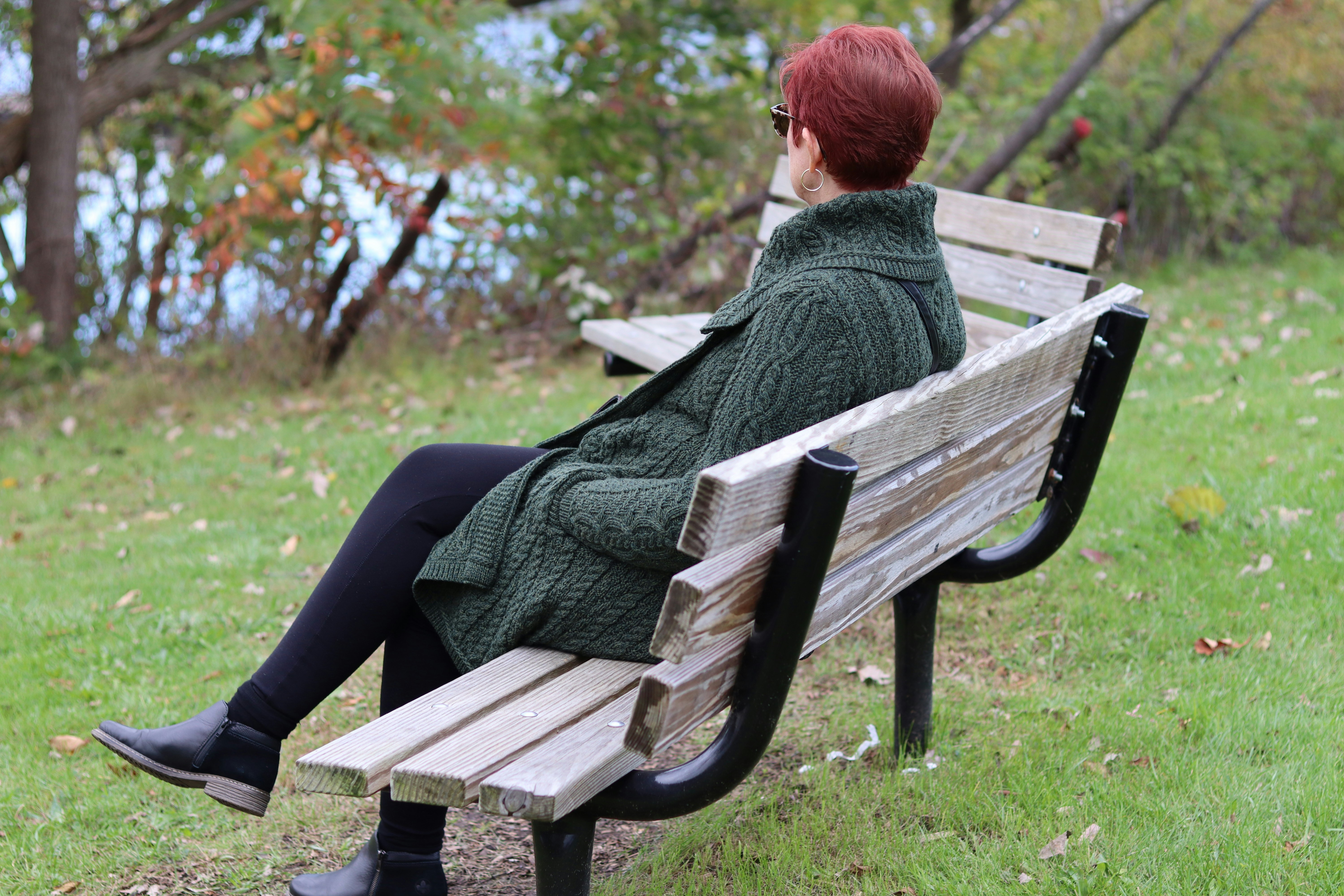 a woman sitting on a wooden bench in a park