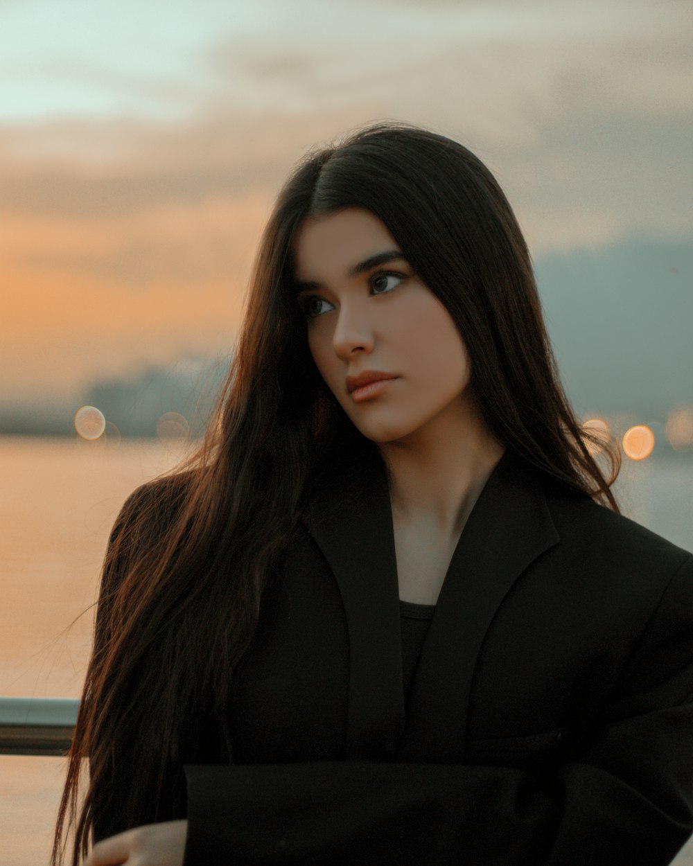 a woman with long hair standing next to a body of water