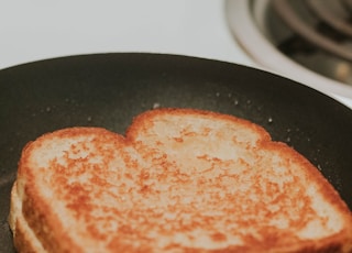 A grilled cheese in a frying pan all done.