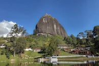 a large rock sitting on top of a lush green hillside