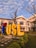 A large sign with the letters 'USL' stands prominently in a landscaped area with green grass and plants. The building behind the sign is an older architectural style with white and red details. The sky is blue with scattered clouds, and there is a leafless tree in the foreground.
