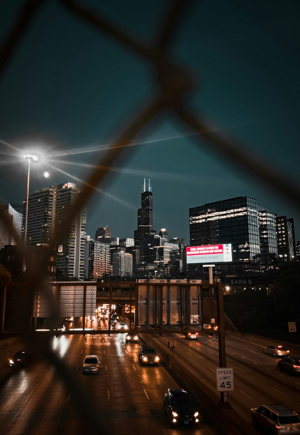 a city skyline seen through a fence at night