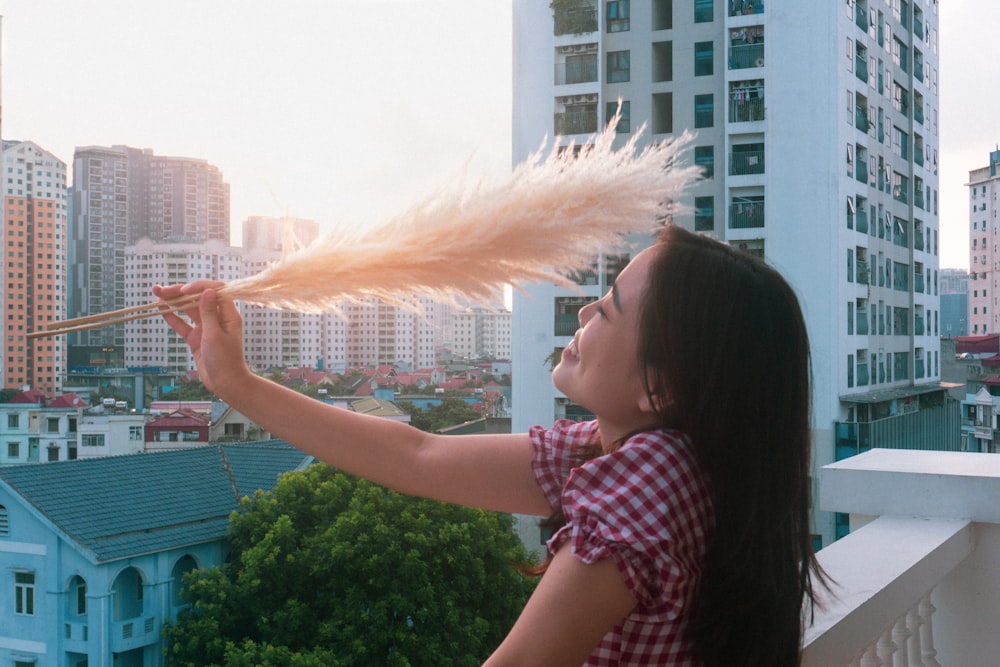 a woman holding a feather in front of a city skyline