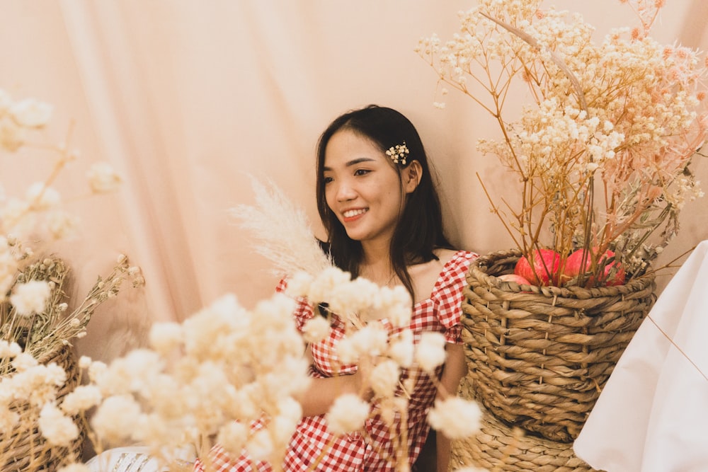 a woman sitting next to a basket of flowers