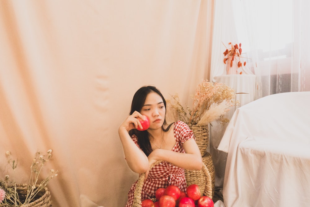 a woman sitting in a chair with apples in front of her