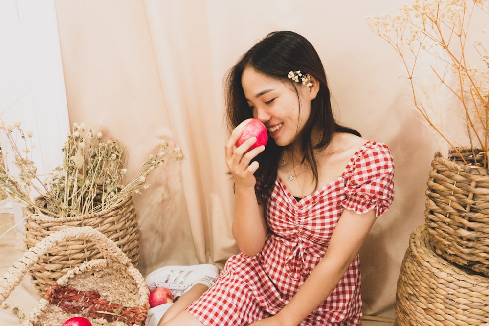 a woman sitting on the floor eating an apple