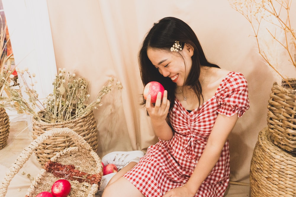 a woman sitting on the floor holding an apple