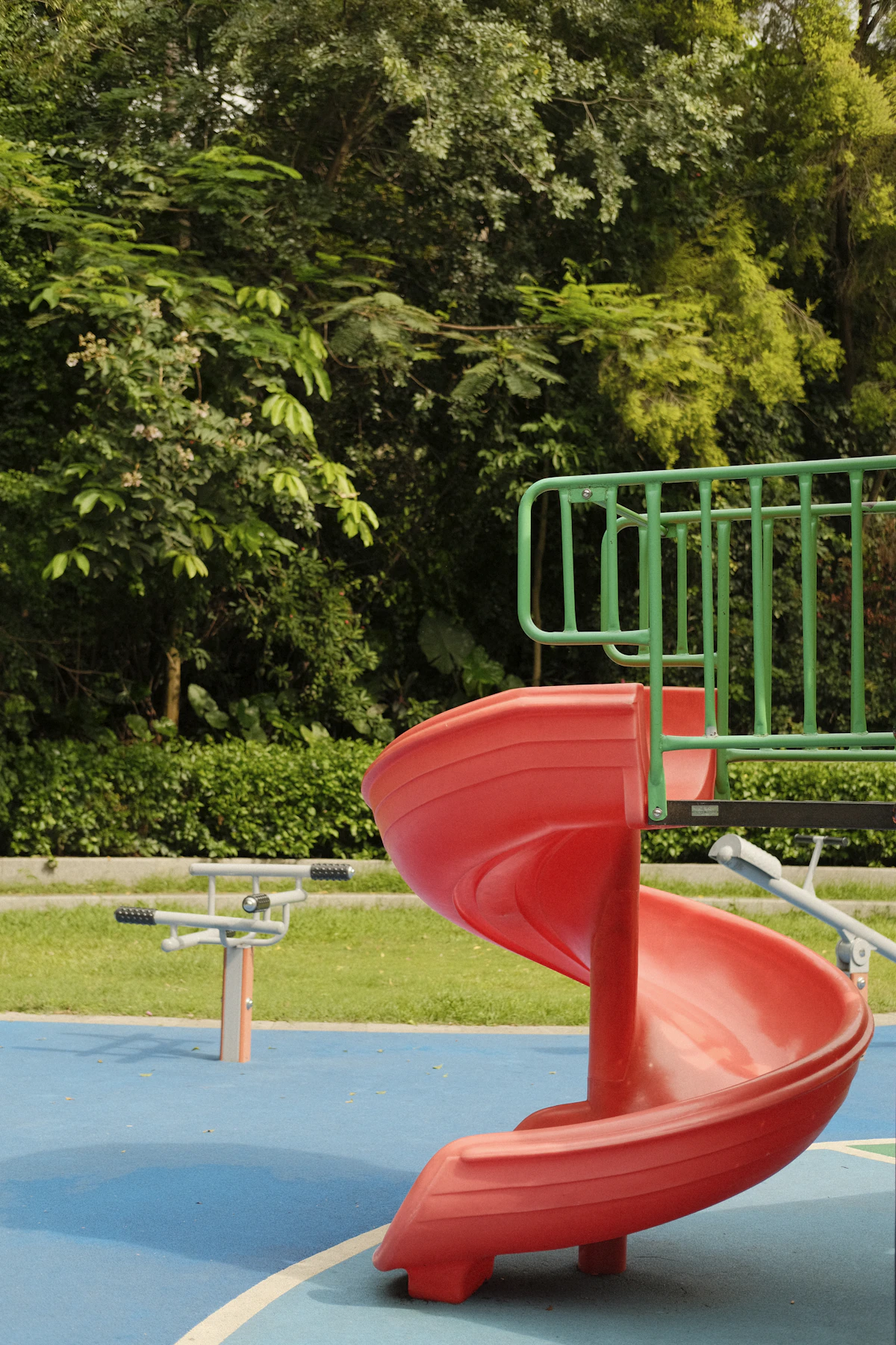 Taman bermain dengan perosotan merah dan pepohonan hijau
