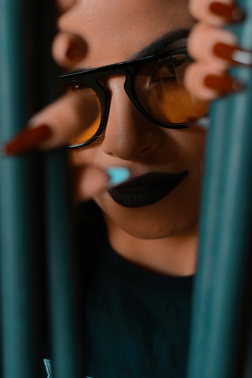 a woman wearing glasses behind bars with her eyes closed