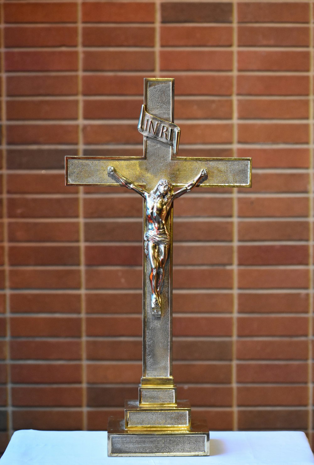 a statue of a crucifix with a brick wall in the background
