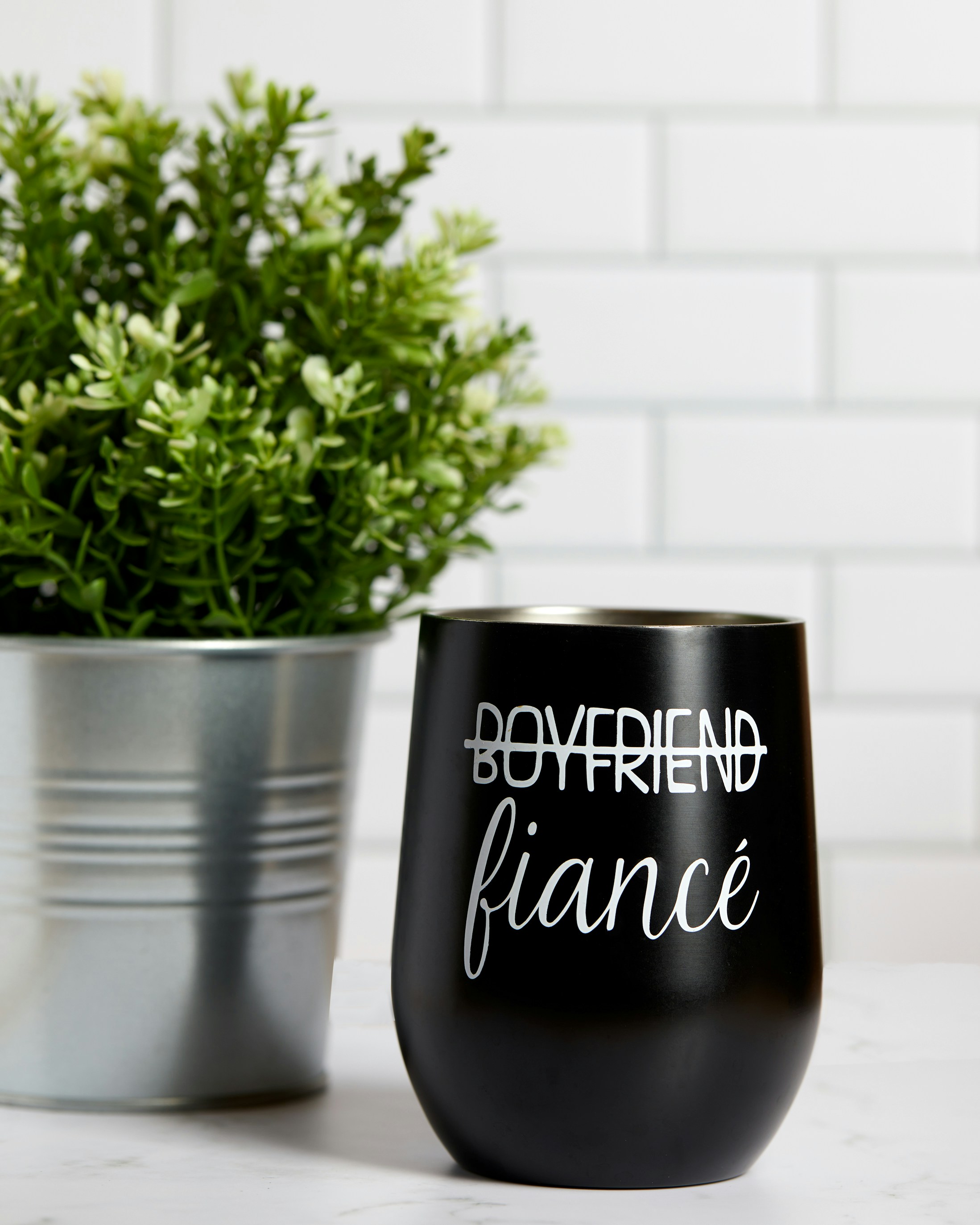 um copo de vinho preto sentado ao lado de um vaso de plantas