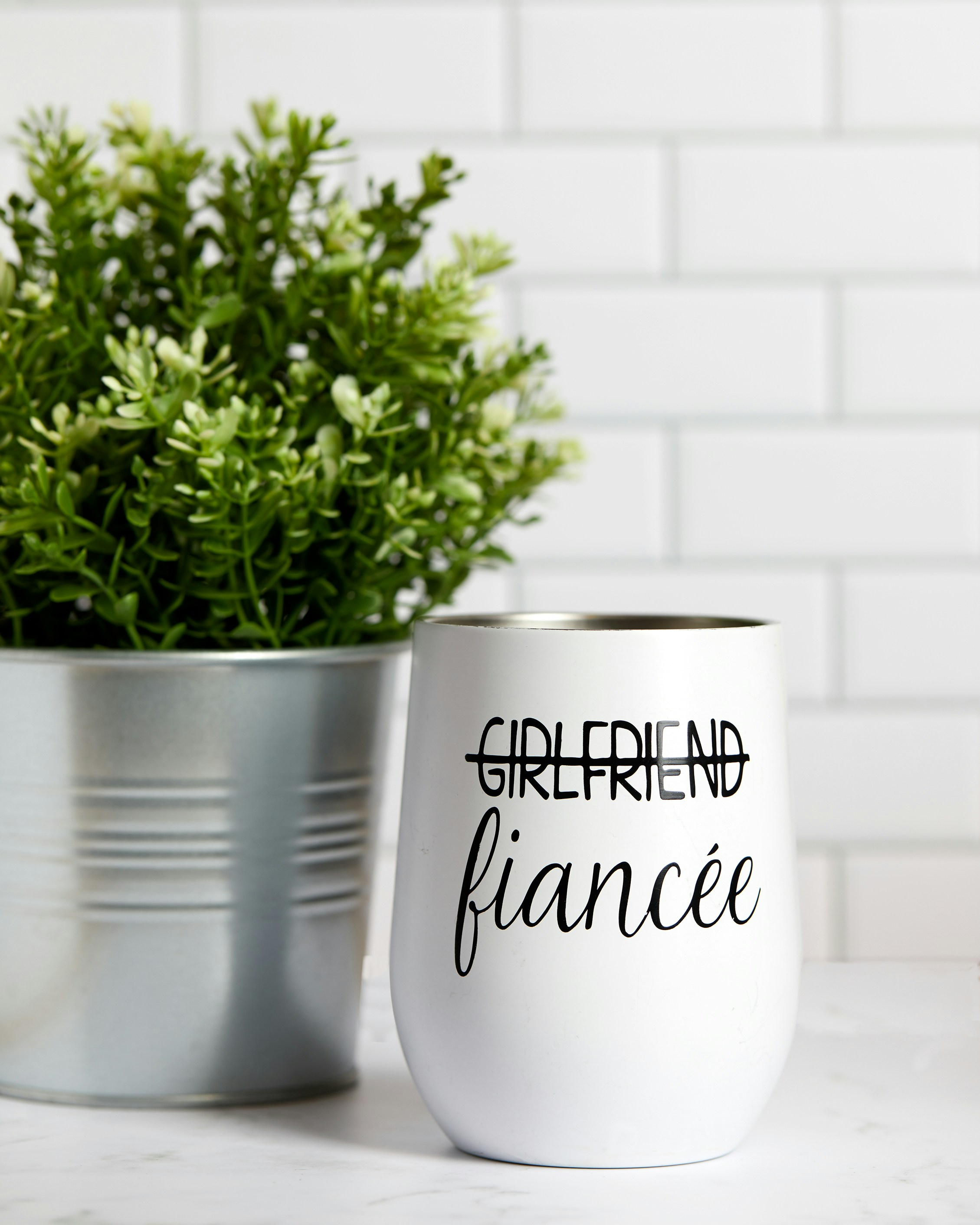 uma planta em um vaso de metal ao lado de uma parede branca