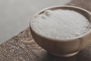 a wooden bowl filled with sugar on top of a wooden table