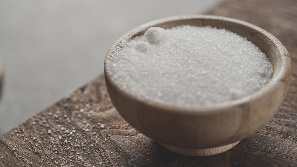 un bol en bois rempli de sucre sur une table en bois