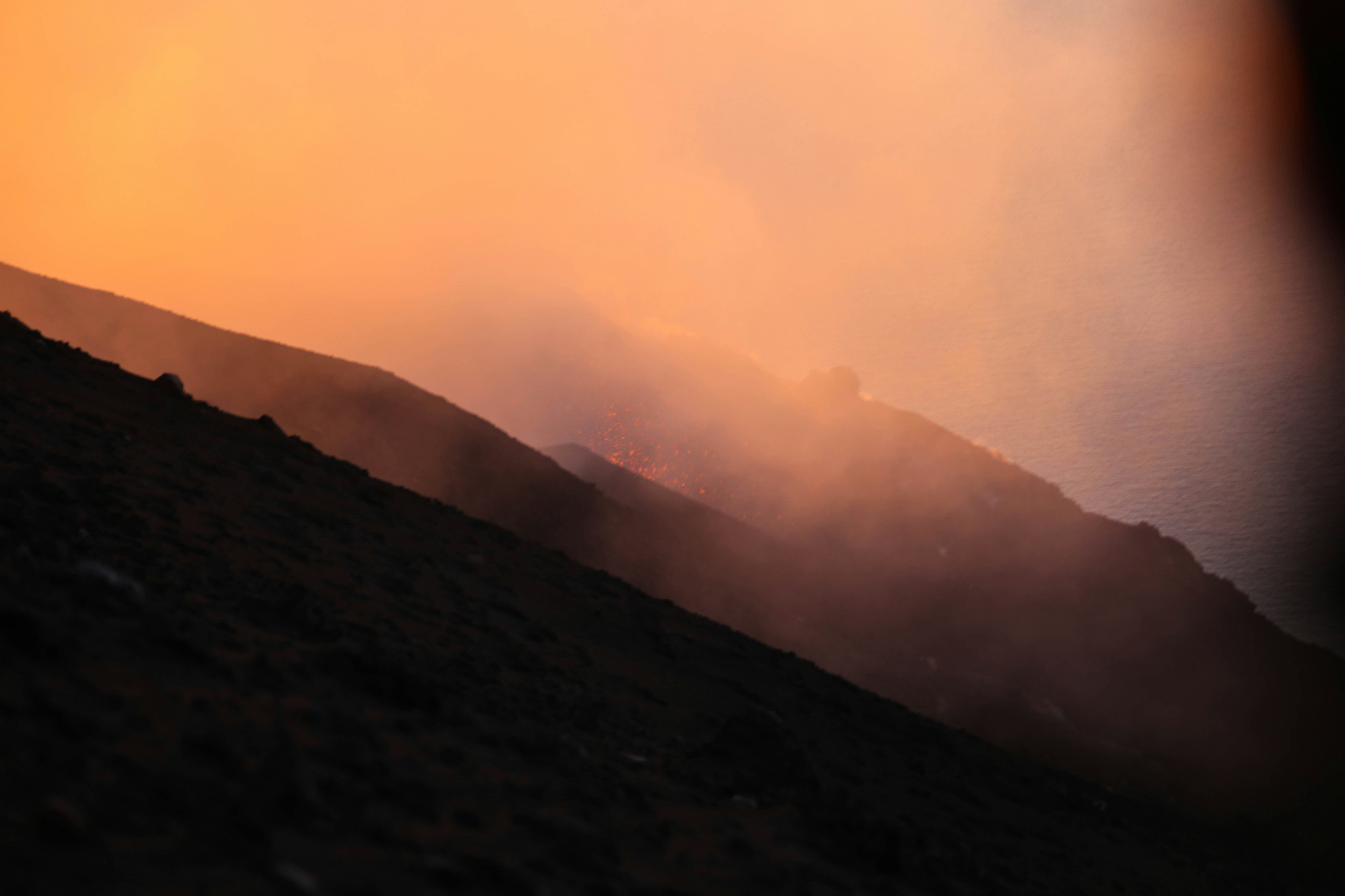 a person standing on a hill with a fire in the background