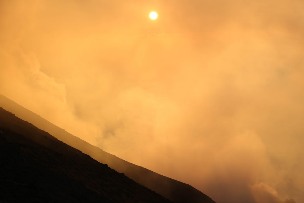 the sun is setting over a hill with a horse in the foreground