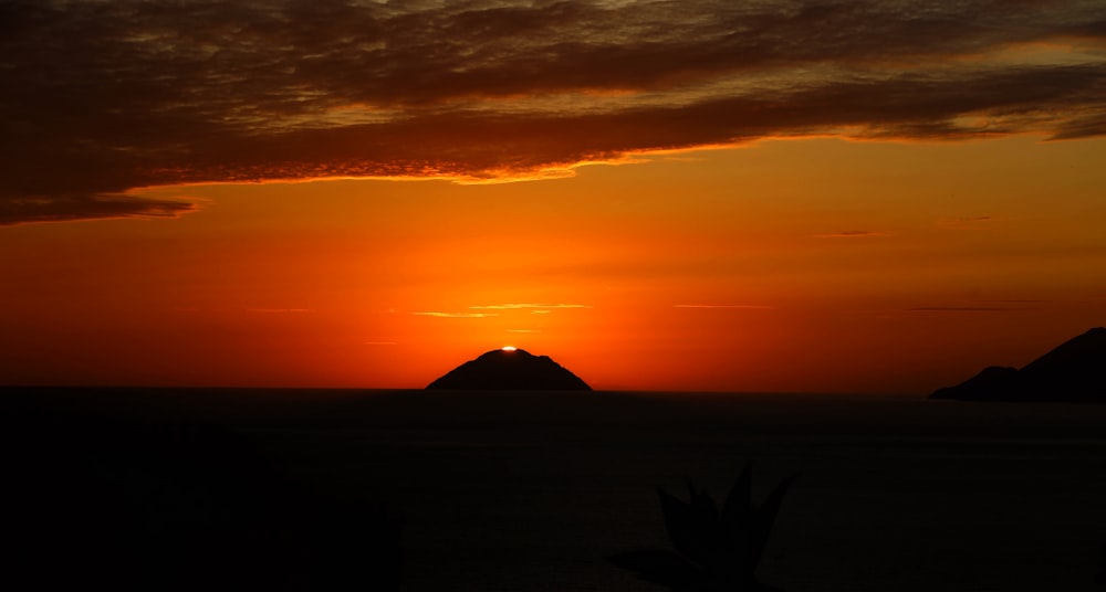 the sun is setting over a small island