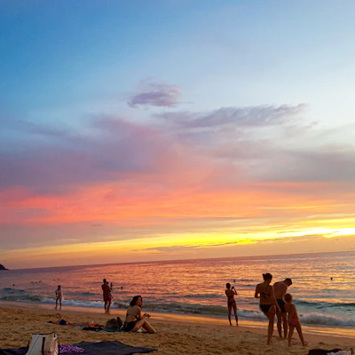A vibrant photo of happy travelers enjoying a sunset on a pristine beach.