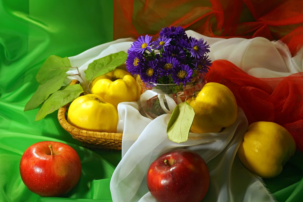 a basket filled with fruit and flowers on top of a green cloth