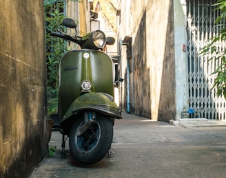 a green scooter parked on the side of a building