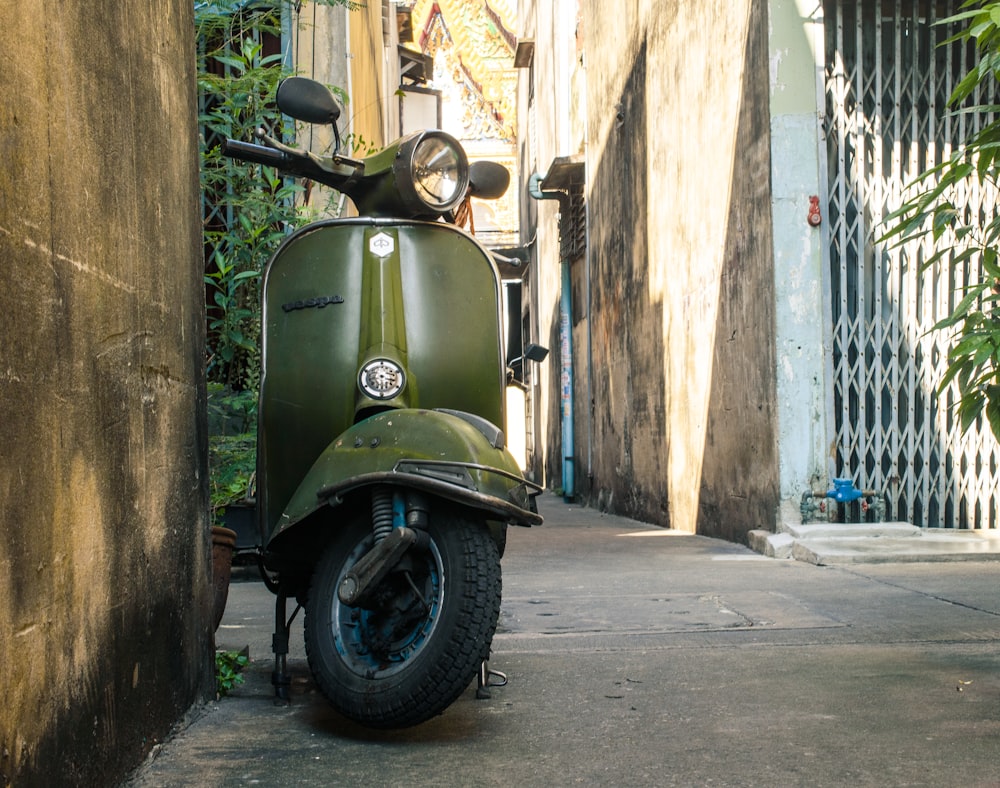 a green scooter parked on the side of a building