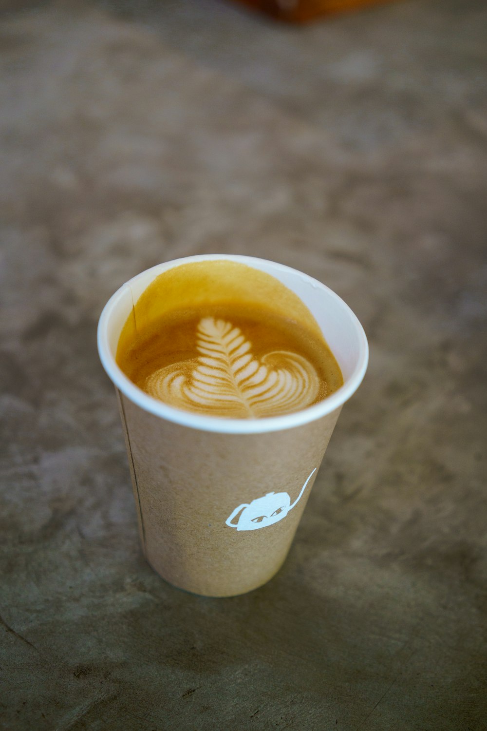 a cup of coffee with a leaf drawn on it