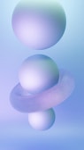 Three spherical objects are arranged vertically with a toroidal shape encircling the middle sphere. The background is a gradient of soft blue and violet hues, creating a smooth and serene atmosphere.