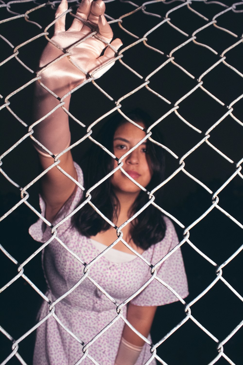 a woman standing behind a chain link fence