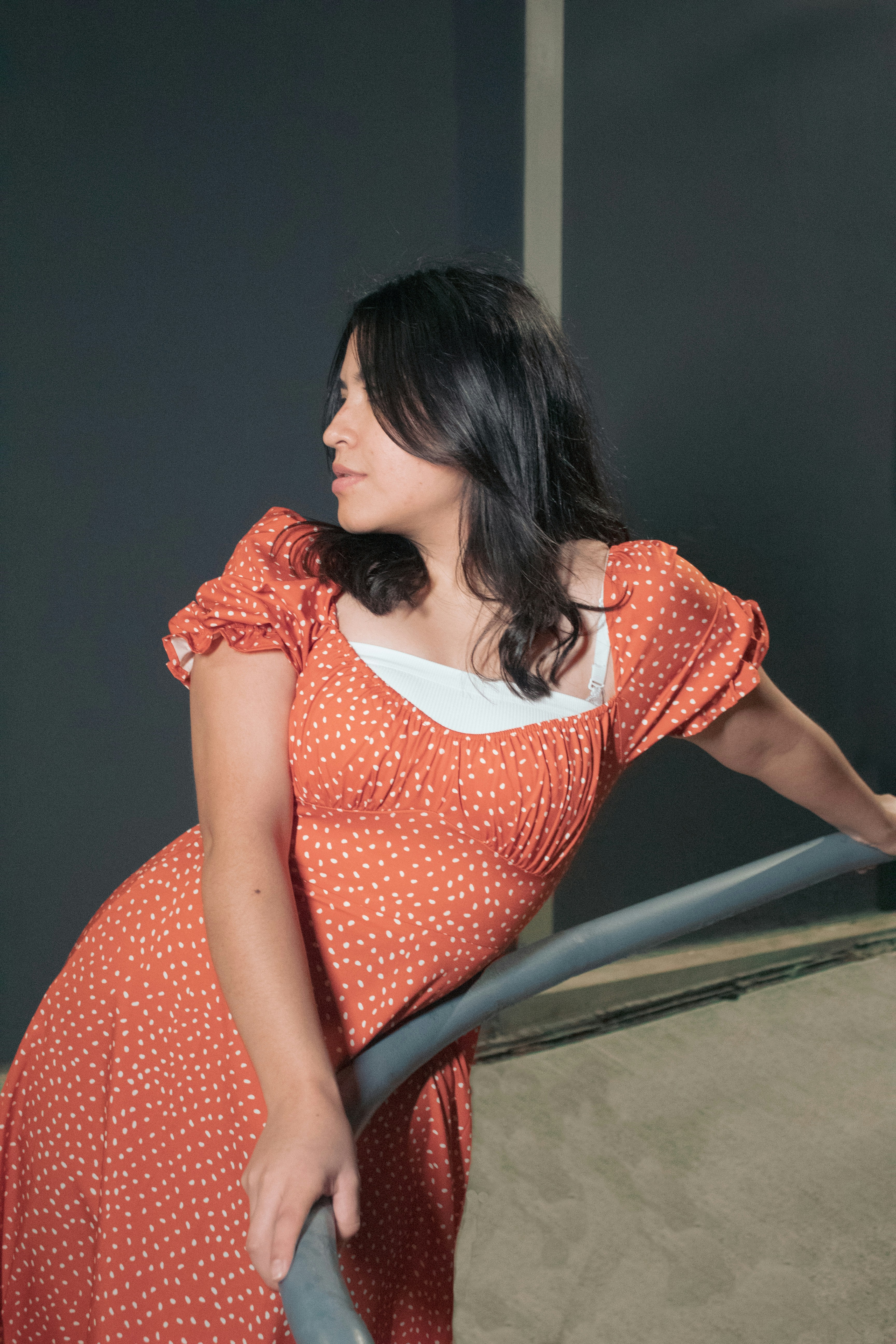 a woman in a polka dot dress leaning on a rail